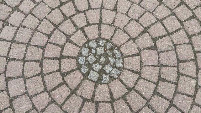 Top view paving stones circular mosaic, closeup overhead shot of concentric cobble rings with beige tiles, gravel filled joints