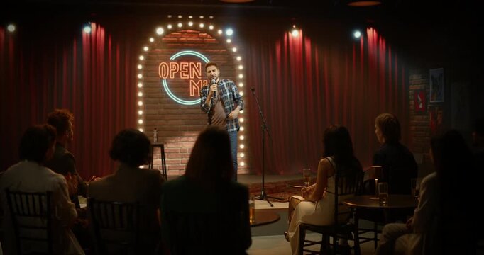Funny Stand-up Comedian Performs at a Live Open Mic Comedy Club, Delivering Punchlines, Crowd Laughing. Playful Jokes as the Audience Laughs, Applauds. Performer Goes on Stage and Starts