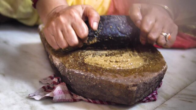 Close up of Indian Woman Hands Grinding Fresh Spices on Traditional Stone Grinder, Manual Food Preparation Using Sil Batta in Indian Kitchen