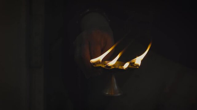 Hands taking Blessing Over Burning pancha pradeep or traditional Oil Lamps in Dark Temple, Indian Hindu Ritual Aarti Ceremony with Golden Flames and Warm Glow