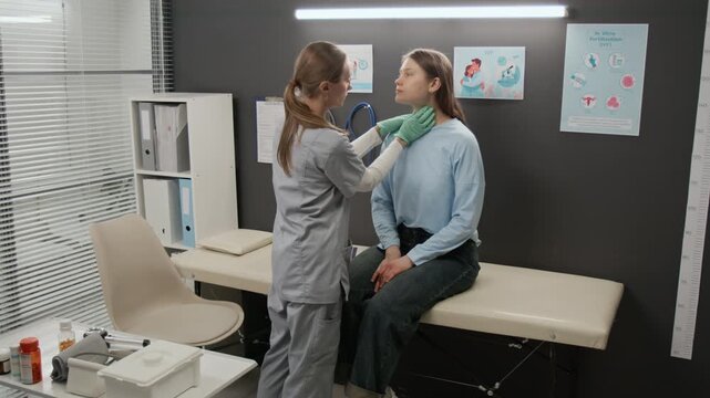 Female medical specialist putting clipboard on couch and examining neck of young woman during preconception checkup in fertility clinic