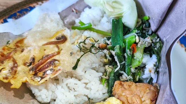 Authentic Indonesian Nasi Pecel with Omelette and Anchovy Peanut Cracker Served on Traditional Brown Paper Wrapper, Healthy Javanese Vegetable Salad Rice Concept for Street Food Industry