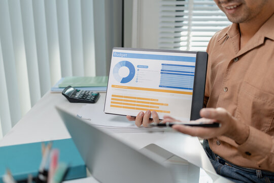 Person presenting budget report on tablet while working with laptop, explaining financial data and expense planning, representing accounting work, finance management, and business decision making.