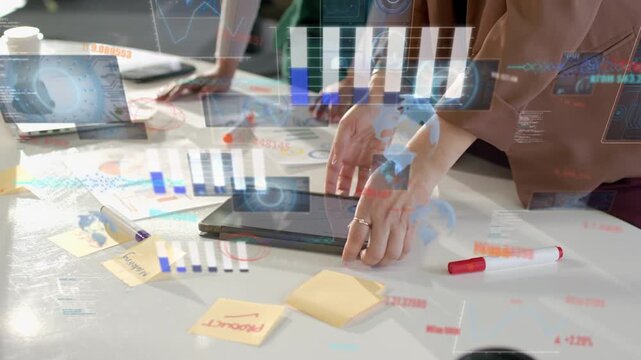 Lead woman tapping tablet causing HUD charts on table, folding, handing device to peer for business