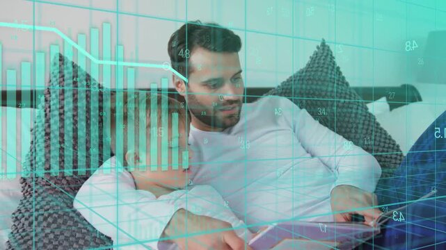 Father tapping tablet on bed while guiding son, teal charts animating over screen teaching finance
