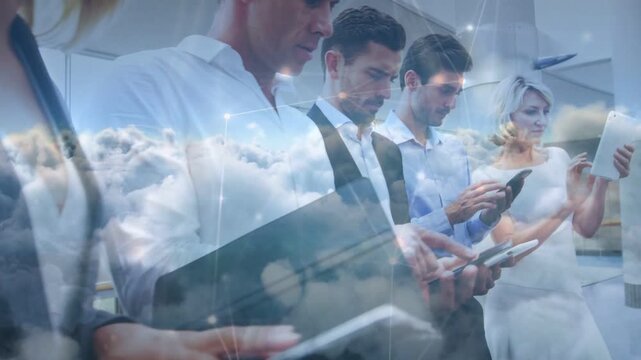 Business team tapping phones and tablets in atrium, camera pulling back showing cloud connectivity