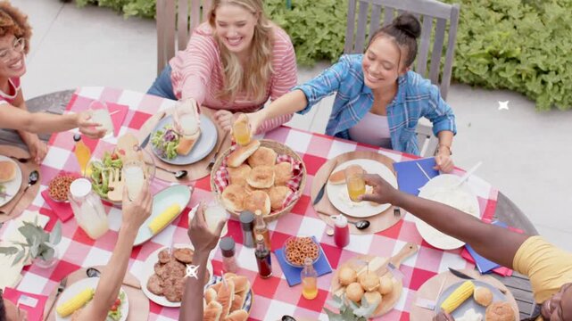 Six adults reaching for glasses on table turquoise graphic radiating revealing group toasting food