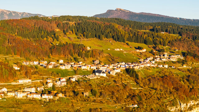 Mountain village of Luserna amidst vibrant autumn forests and green hills, a picturesque tourism destination in Alpe Cimbra, Trentino, Italy.