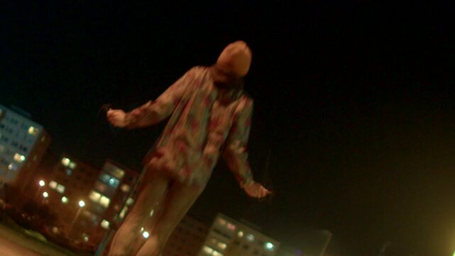 Nighttime street rapper delivering energetic verse under orange lights, lowangle cityscape shot shows beanie and patterned jacket, dynamic hand gestures and confident pacing
