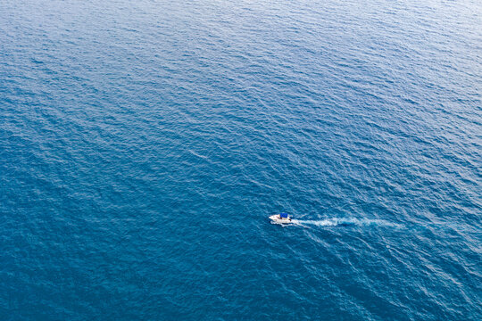 Drone aerial view of sandy beach and blue sea captured from above on hot summer day. The composition shows water with vibrant colors and natural patterns. Summer travel, vacation and tourism concept.