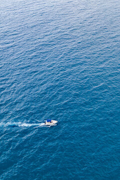 Drone aerial view of sandy beach and blue sea captured from above on hot summer day. The composition shows water with vibrant colors and natural patterns. Summer travel, vacation and tourism concept.