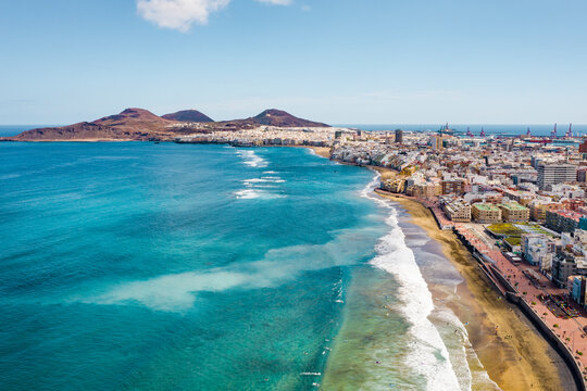 Drone aerial view of a sandy beach and blue sea captured from above on a hot summer day. The composition shows the meeting of shoreline and water with vibrant colors and natural patterns. Perfect conc