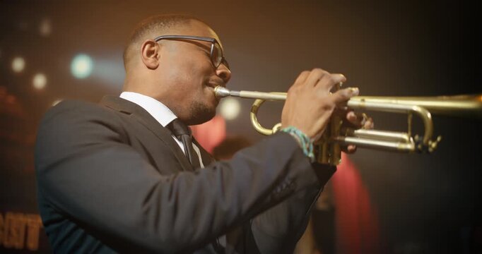 Black Male Trumpet Player Leads a Live Jazz Band Concert in a Bar, Playing an Expressive Song on Stage as the Audience Watches This Intimate Music Event at Stylish Club. Cinematic Handheld