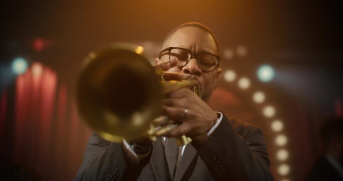 Black Male Trumpet Player Leads a Live Jazz Band Concert in a Bar, Playing an Expressive Song on Stage as the Audience Watches This Intimate Music Event at Stylish Club. Cinematic Handheld