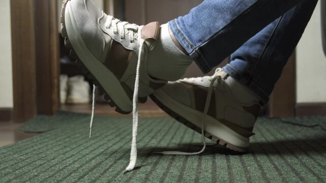 Casual sneakers on feet with untied shoelaces while sitting indoors at home