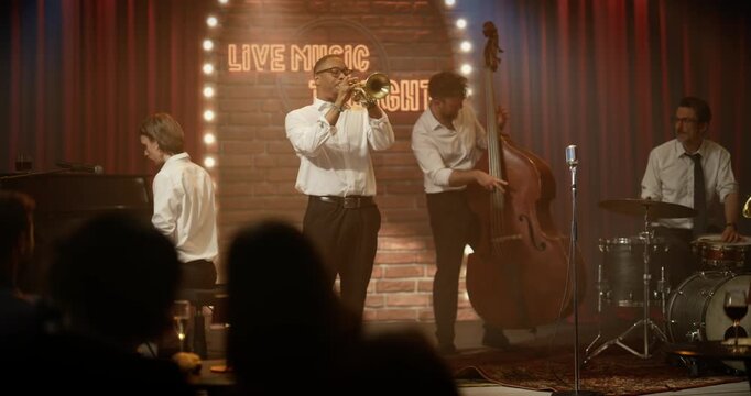 Live Jazz Concert at a Bar Stage as a Trumpeter Leads the Band, Playing a Vibrant Song With Piano, Bass, Drums and Sax While the Audience Enjoys the Night Music Event.
