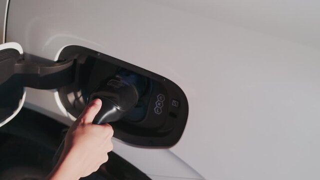 4K slow motion person charging electric car at home.