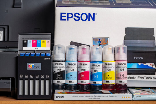 Close up of Epson 108 ink bottles and EcoTank L8050 photo printer. Concept of home printing maintenance and continuous ink supply system setup