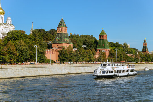 Moscow, Russia - September 11, 2025: Taynitskaya and Unnamed towers of the southern Kremlin wall on the Kremlin Embankment of Moscow river. The Flagman pleasure boat on the river.