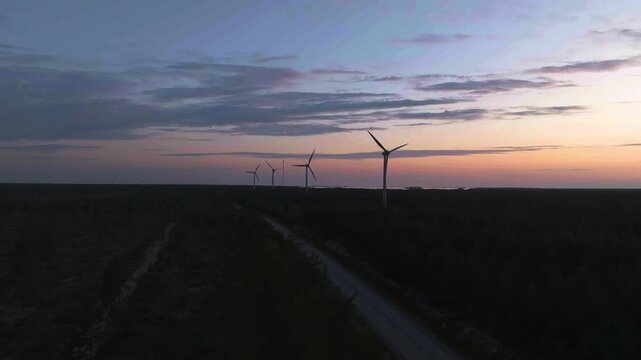 Aerial drone view approaching wind turbines and a road at dusk in Hanko, Finland
