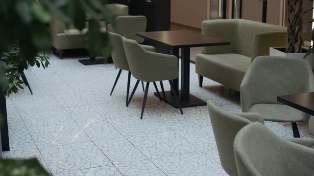 Tilt up slowmo no people shot of coworking space interior with modern furniture and lush green plants