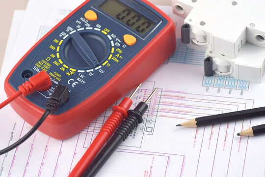 The digital multimeter electrical engineering drawings, circuit breaker and pencils.