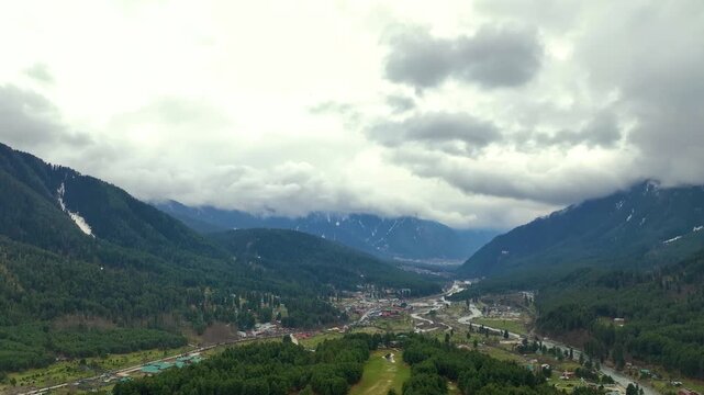 Aerial pullback shot from a high altitude, revealing the immense scale of Pahalgam and the scenic Lidder Valley in Jammu and Kashmir, India.