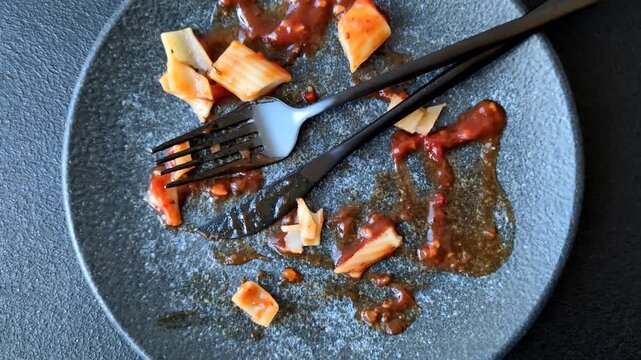 A dirty plate after a meal with leftover pasta and tomato sauce, clutter, cleaning, household chores. An empty dirty plate as a background for your design