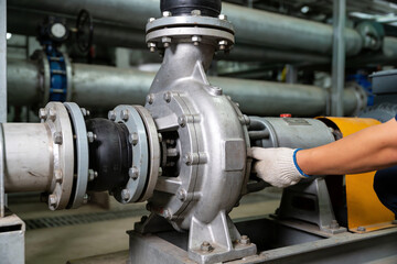Obraz premium Industrial worker performing maintenance on a large pump with a wrench in a factory setting