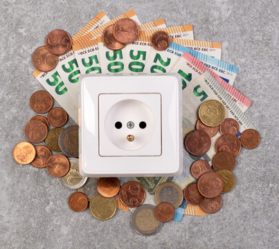 Cost of electricity concept, plastic power outlet and money on a gray stone background