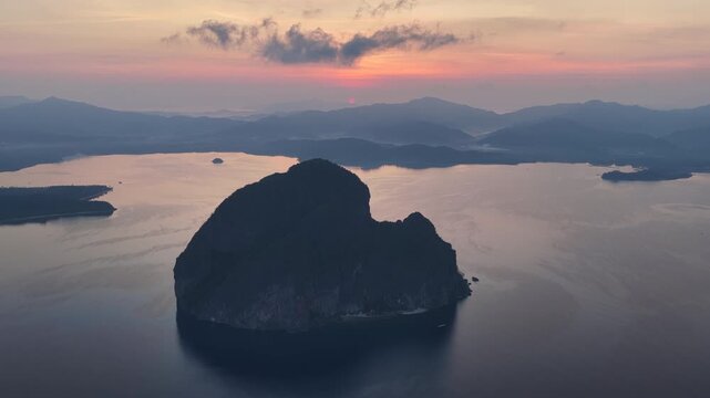 Sunrise silhouettes dramatic limestone islands in Bacuit Bay, El Nido, at sunset. This area in the Philippines is a popular vacation destination due to its coral reefs, beaches, and hidden lagoons.