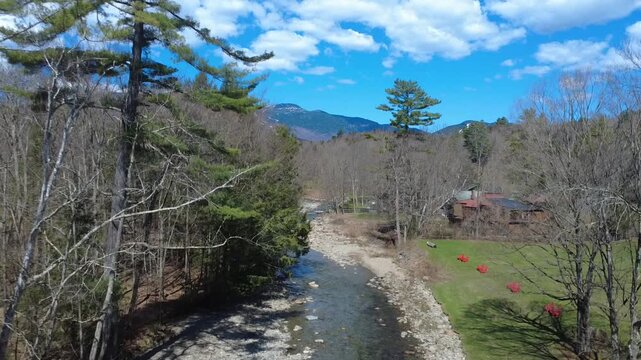From rocky stream in a forest to snow covered mountains reveal, flying up with a drone in Vermont