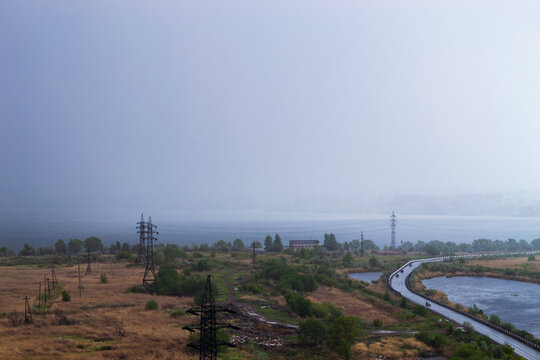 Rainstorm over lake and industrial cityscape