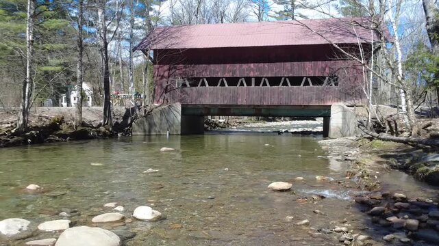 incredible drone fly under a bridge, inches off the water of this historic Vermont scene