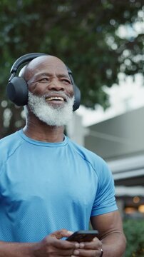 Phone, fitness and black man outdoor with texting, networking or communication on mobile app. Headphones, sports and mature male person with cellphone for contact, email or social media in nature.