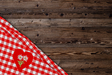 Obraz premium Red checkered tablecloth with floral heart patch placed on wooden table at a gathering in the afternoon