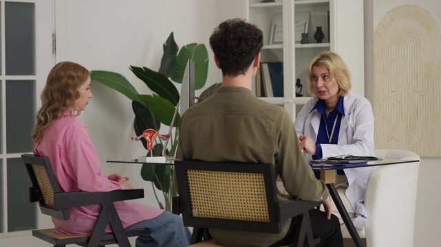 Female gynecologist consulting young couple during fertility check-up in clinic