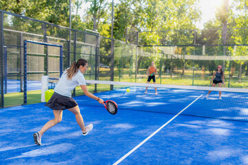 Obraz premium Forehand shot during outdoor padel doubles match, wide view with opponents on the other side of the court, dynamic gameplay moment.