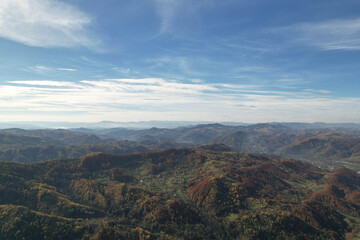 Fototapeta premium High angle aerial view of autumn mountain ridges under blue sky