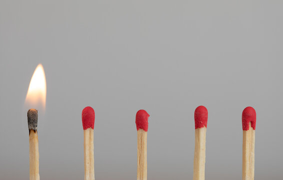A burning match leading a line of unlit matches representing initiation and progress.