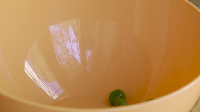 Green_peas_macro_falling_into_pale_orange_bowl_10bit_120fps