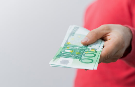 Close up of person's hand holding a wad of Euro banknotes, representing finance and payment