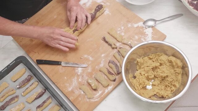 Top view of woman hands shaping cookie dough. The overhead perspective emphasizes precision, repetition, and the artisanal process of homemade baking.