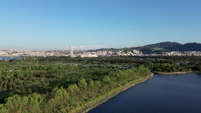 Aerial view of a lush green park with a serene blue lake and distant cityscape