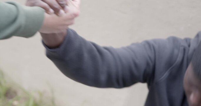 Close-up of hands as a friend helps another up from the ground. The gesture highlights empathy, solidarity and human connection, focusing on touch, trust and emotional support.
