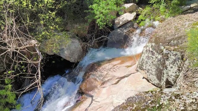 Corrente de &aacute;guas cristalinas serpenteando por entre penhascos de granito e vegeta&ccedil;&atilde;o ribeirinha em meio &agrave; natureza