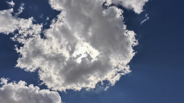 A cinematic timelapse follows rapidly shifting clouds with the sun glowing behind dark formations. The intense atmospheric motion provides a powerful weather transition.