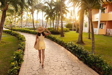 Young woman in straw hat walking along tropical resort path, rear view © Home-stock