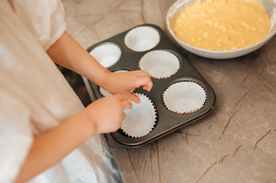 Caucasian Child Placing Cupcake Liners On Tray, Hands Gently Pressing Paper Cases Into Metal Muffin Tin