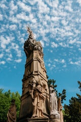 Fototapeta premium Historic monument with religious sculptures in Subotica, Serbia beneath a vivid blue sky. Sacred heritage and artistic stonework in a city park.
